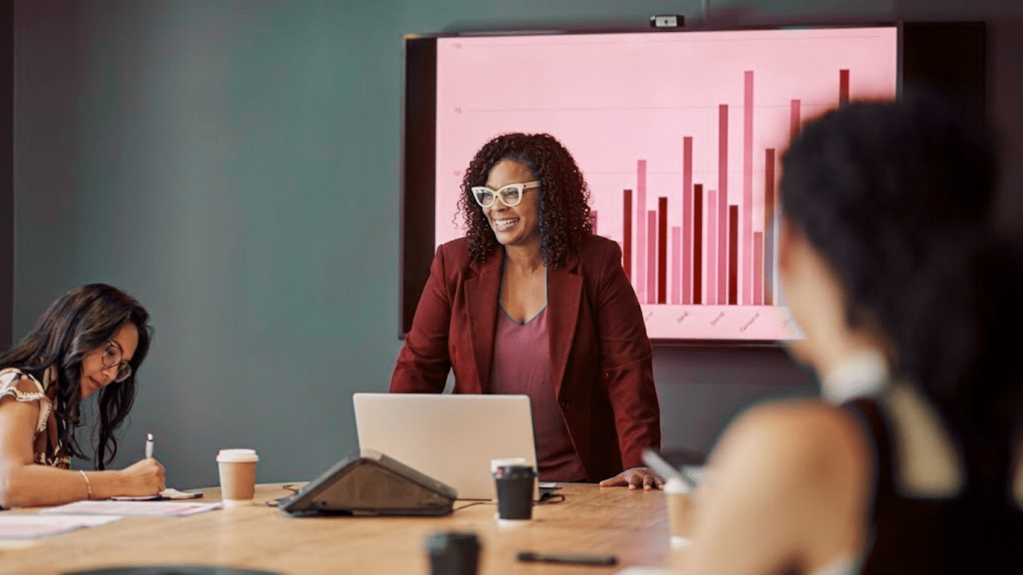 a woman presents professional development goals data to a team in a modern office
