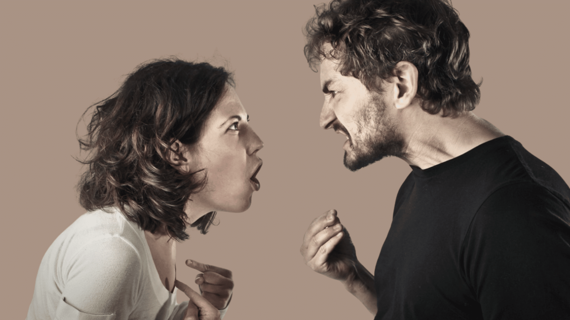 an angry man and woman shouting directly at each other in a heated argument against a plain gray wall
