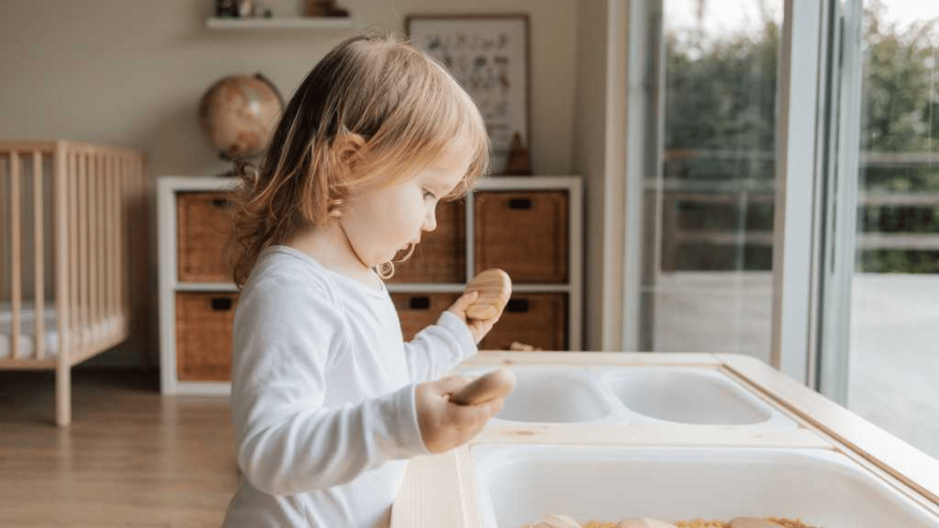 child engaged in focused sensory play activity near window using wooden toys in a calm home environment for learning development