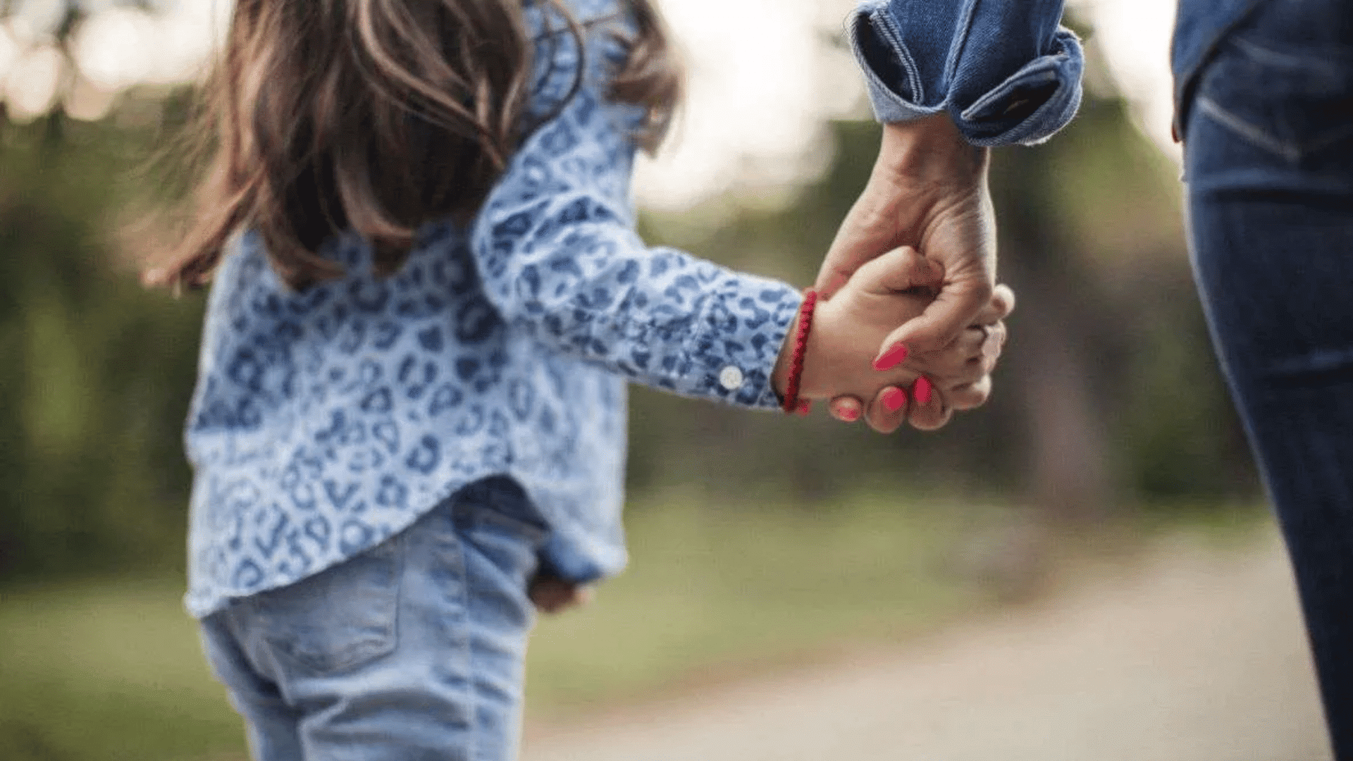 child holding an adults hand while walking outdoors showing care trust safety and family support in daily life