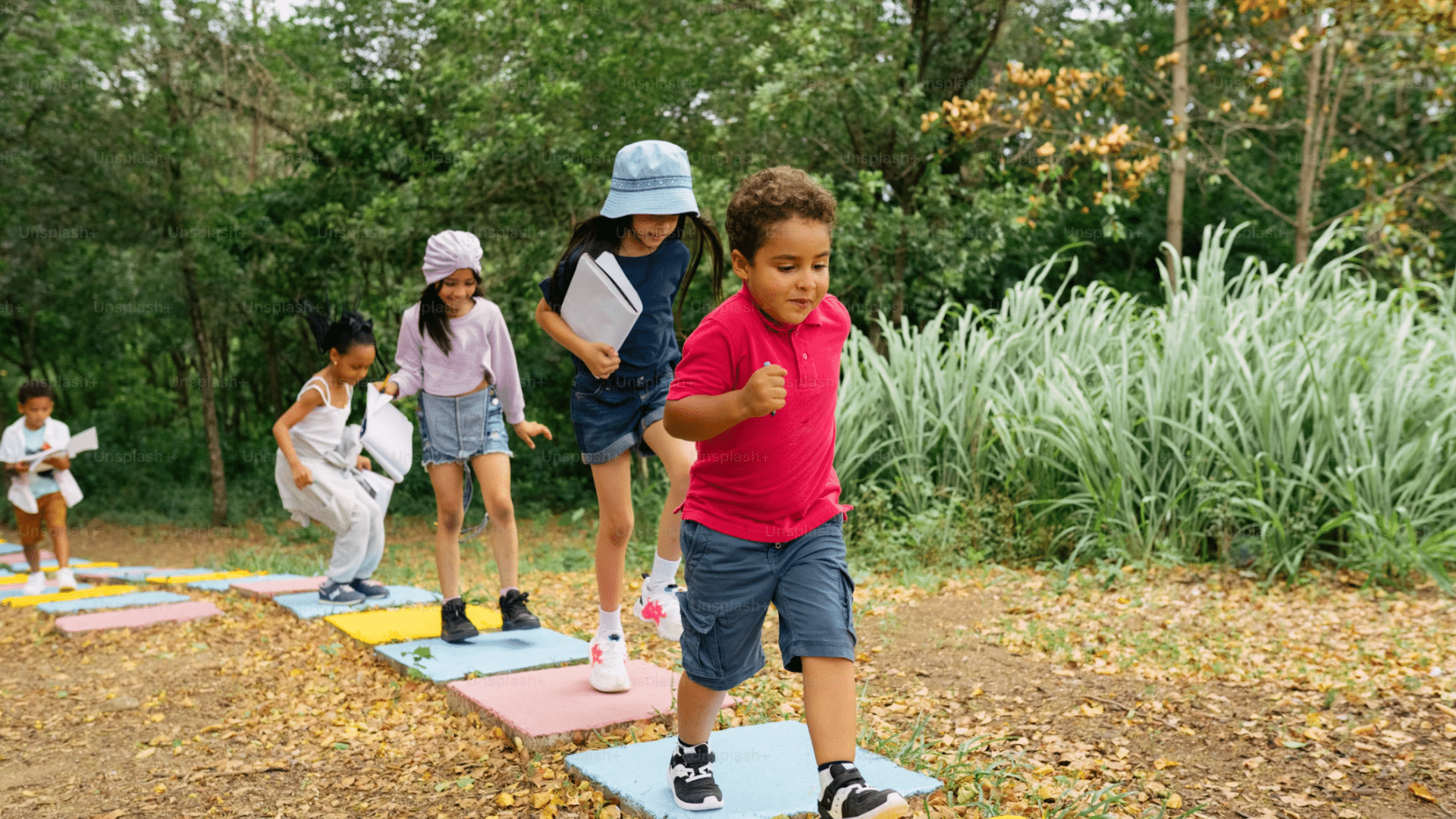group of children walking and balancing across colorful stepping stones on a nature trail during an outdoor activity