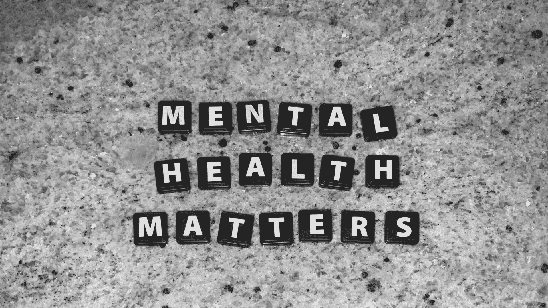 letter tiles spelling mental health matters arranged on a textured stone surface highlighting mental wellbeing awareness