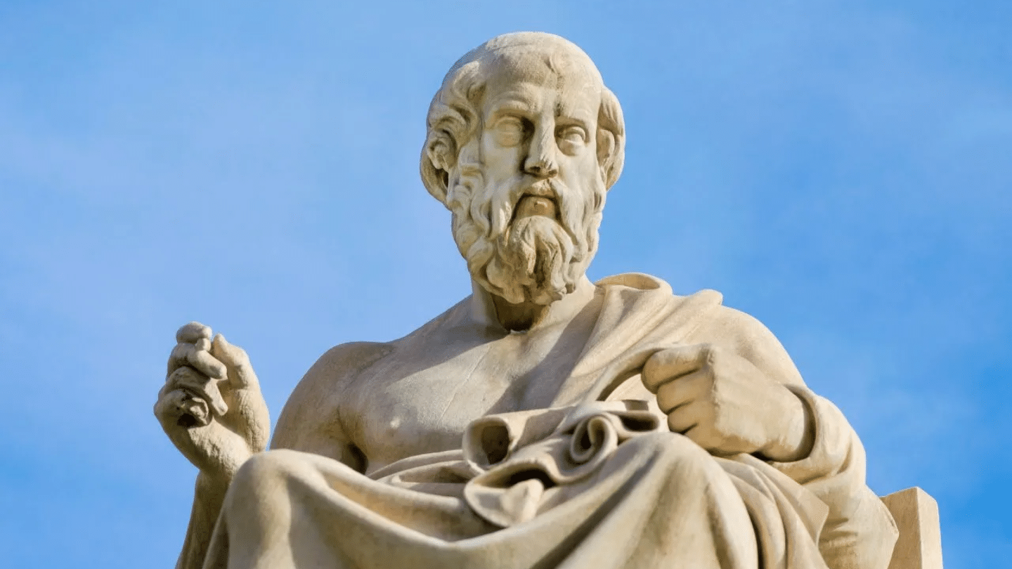 low angle shot of a stone statue of plato holding a scroll under a blue sky