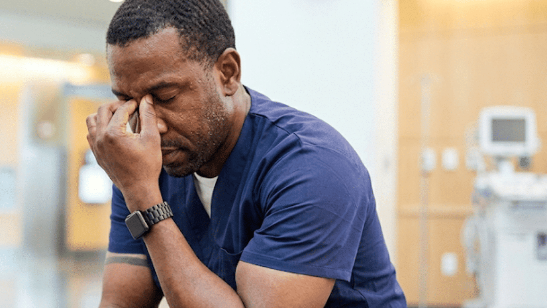 man experiencing stress and emotional exhaustion while sitting in a healthcare setting