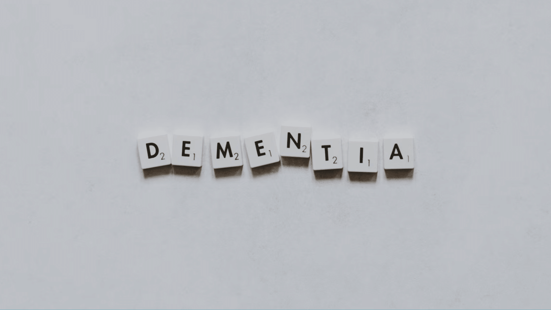 the word dementia spelled with letter tiles centered on a plain white background with ample empty space around it