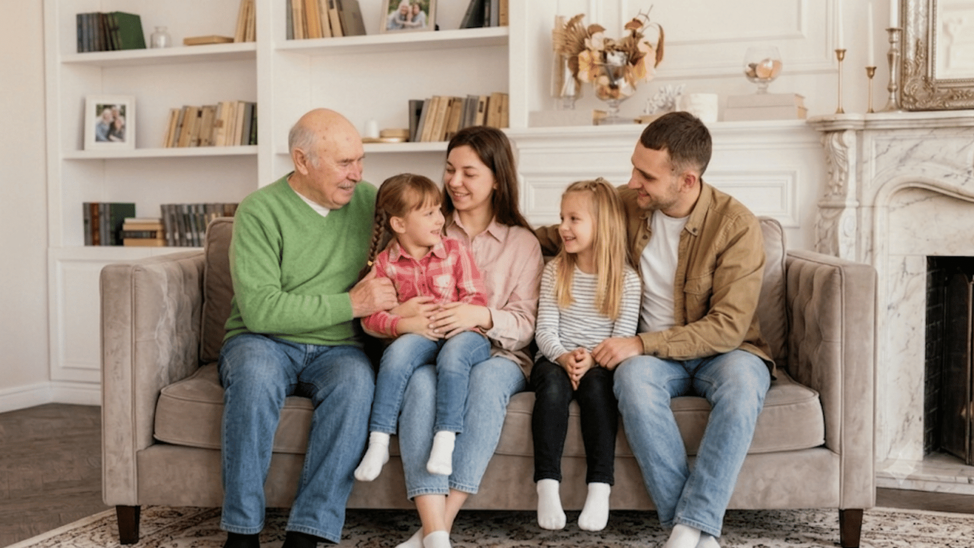 three generations of family sitting together on a sofa smiling and enjoying quality time in a bright cozy living room