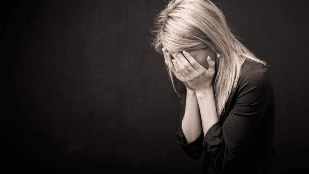 woman covering her face while experiencing emotional distress grief or anxiety related to betrayal trauma and relationship difficulties