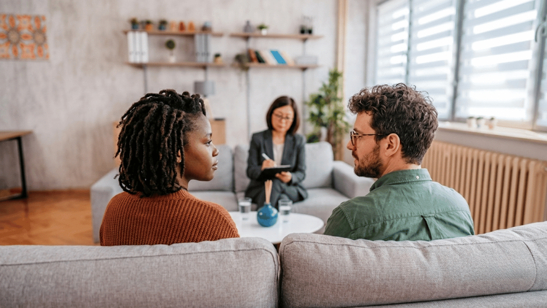 couple attending marriage counseling session with therapist discussing relationship challenges in a comfortable office setting